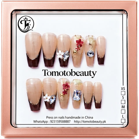 Tomoto Beauty C106 – Mocha Brown French Tip Floral Press On Nails. Elegant nude and chocolate brown French-tip coffin nails embellished with 3D red flowers and crystal gemstone accents.