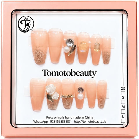 Tomoto Beauty C109 – Peach Glitter Rhinestone Press On Nails. Delicate blush peach and sparkling champagne-glitter coffin nails embellished with faceted crystals, pearl and translucent bow charms.